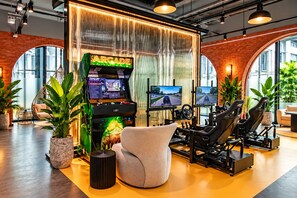 A gaming area with arcade machines, racing simulators, and comfortable seating. - Title Legendary Apartment by TVC (Tambon Choeng Thale)