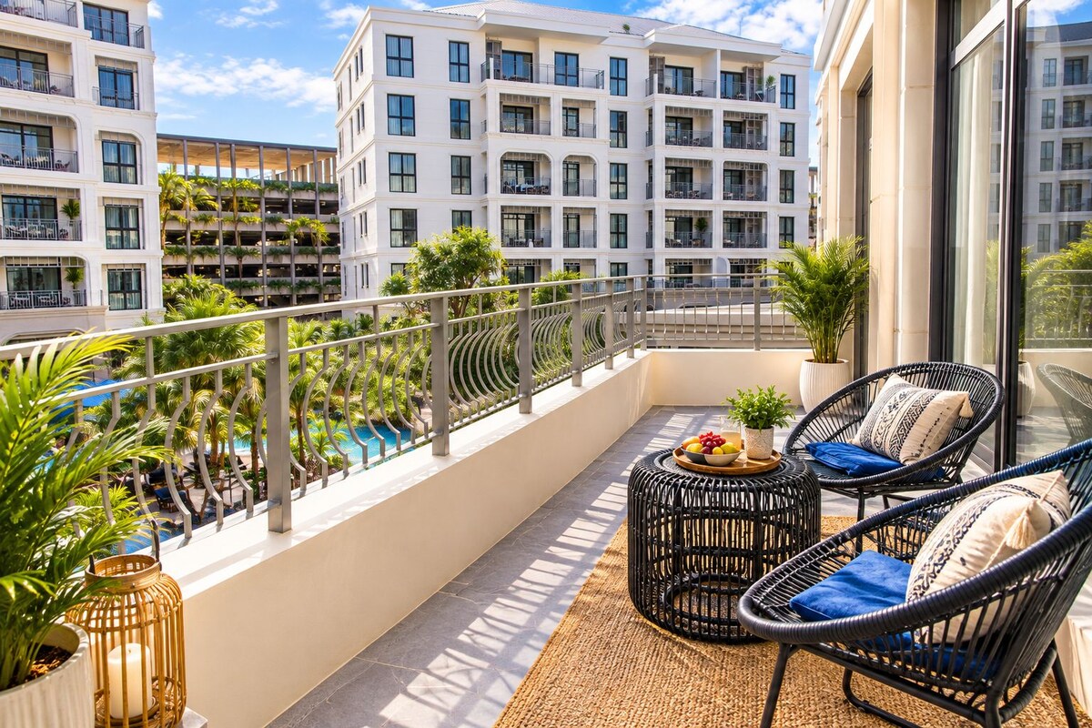 A balcony with wicker chairs, a small table with fruit, and a potted plant.
