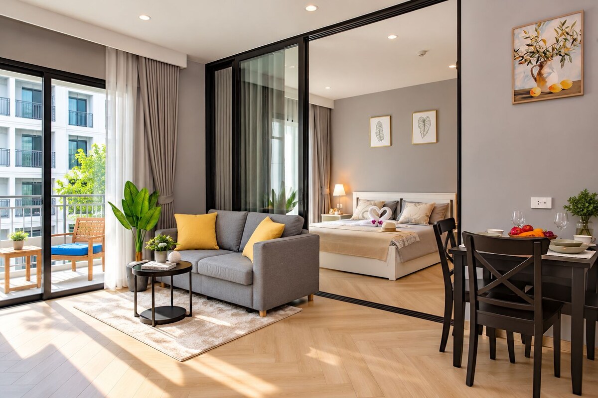 A modern hotel room with a sofa, a dining table, and a bed.