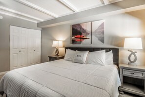 A hotel room with a large bed, two bedside tables with lamps, a wardrobe, and a painting on the wall. - Updated Ski-in/ski-out 2BR condo,mntn vws, 3 hot tubs,1 summer pool,arcade games located in 1849  #107 (Mammoth Lakes)
