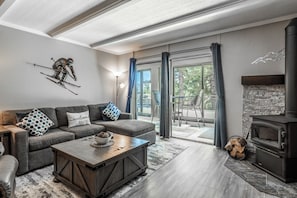 A modern living room with a sofa, coffee table, and fireplace. - Updated Ski-in/ski-out 2BR condo,mntn vws, 3 hot tubs,1 summer pool,arcade games located in 1849  #107 (Mammoth Lakes)