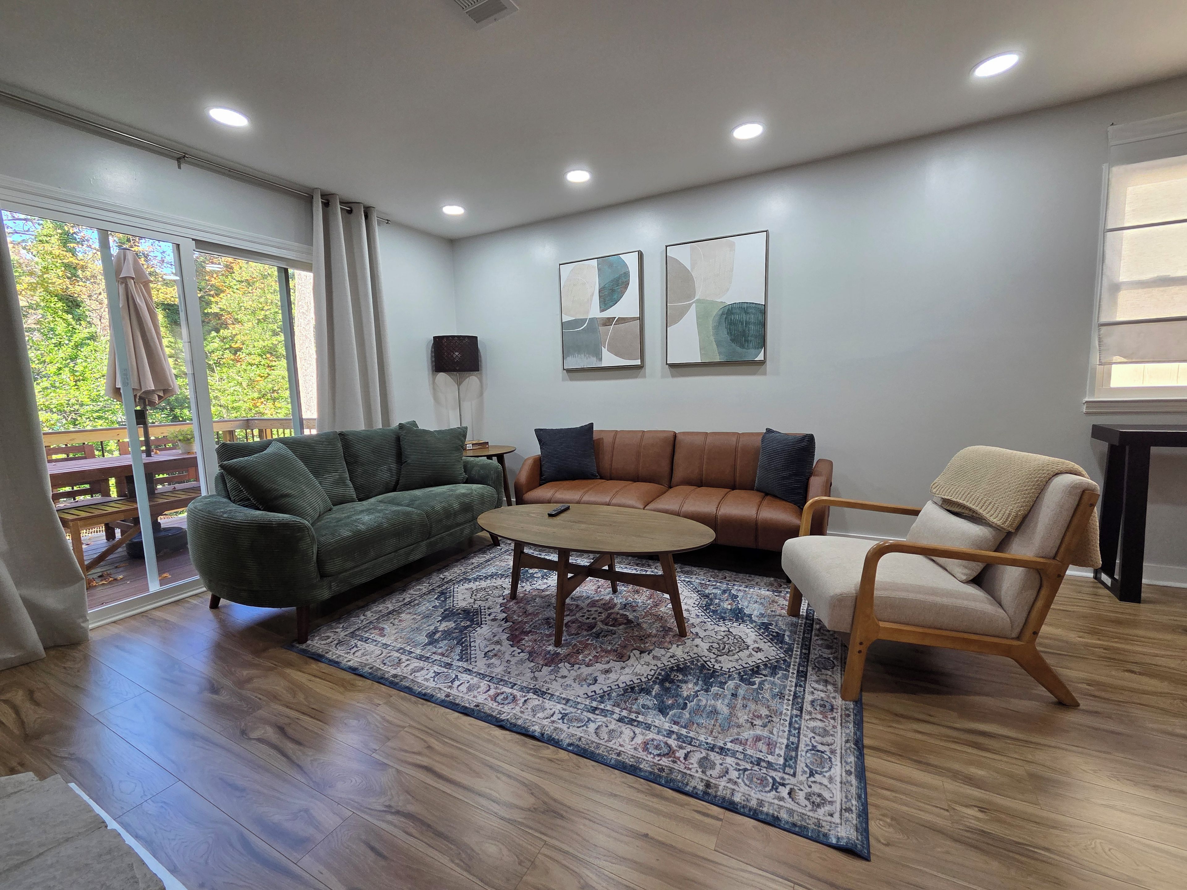 A living room with a green sofa, a brown leather sofa, a round coffee table, and a patterned rug.