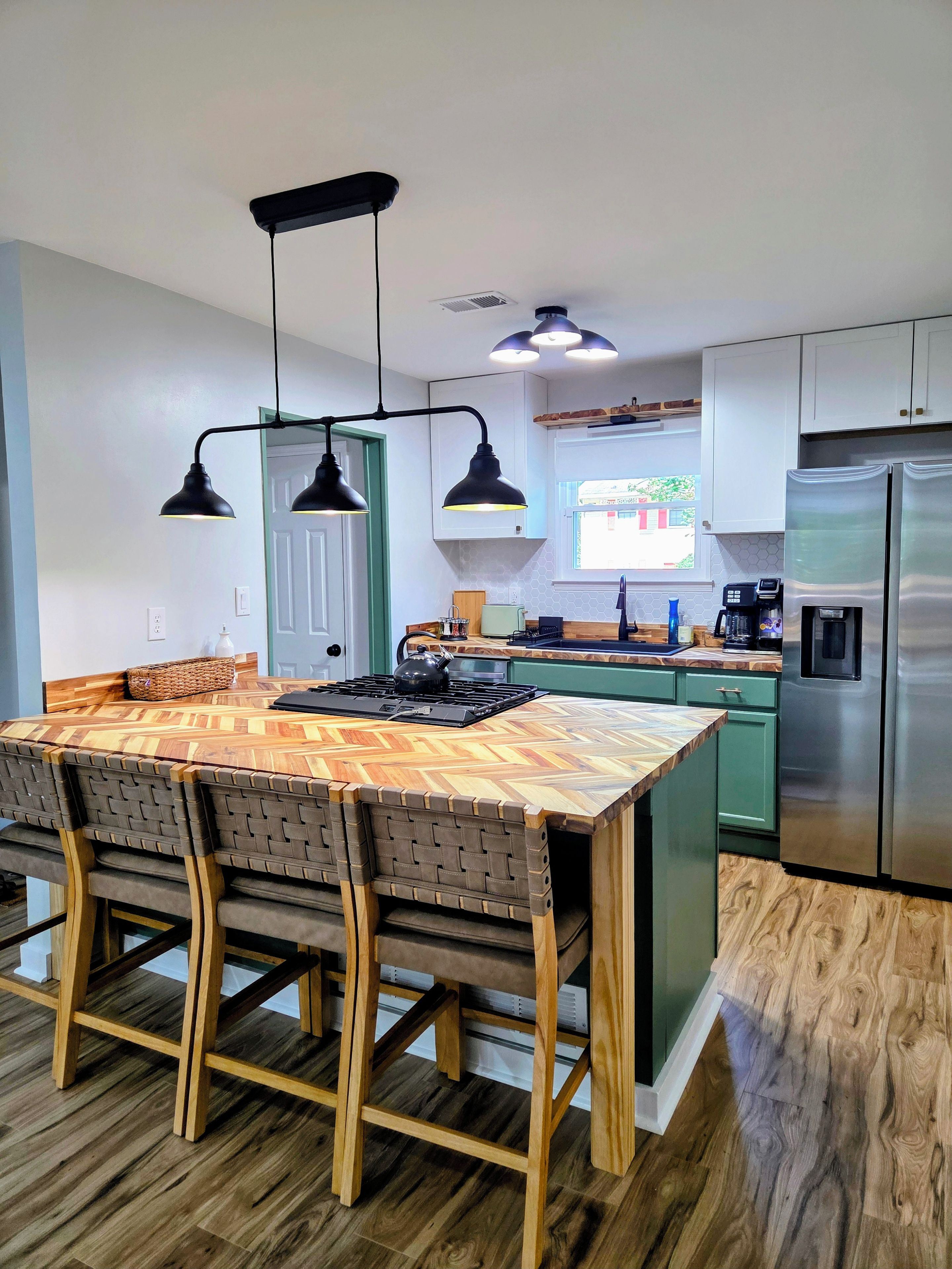 A modern kitchen with a wooden island, pendant lighting, and stainless steel appliances.