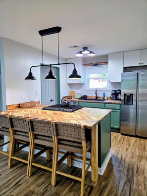 A modern kitchen with a wooden island, pendant lighting, and stainless steel appliances. - Stylish renovated 2BR - 5 min drive to Truist Park (Smyrna)