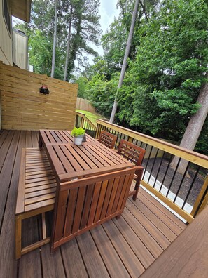 A wooden deck with a table and chairs, surrounded by a wooden fence and trees. - Stylish renovated 2BR - 5 min drive to Truist Park (Smyrna)