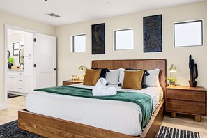 Una habitación de hotel con una cama grande, mesitas de noche, un armario y obras de arte en las paredes.