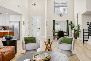 A spacious living area with a dining table, two armchairs, a coffee table, and a kitchen in the background. - Casa Saguaro Old Town: 6BR Heated Pool Hot Tub (Scottsdale)