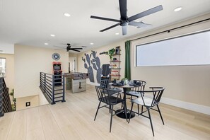 A modern interior with a dining area, ceiling fans, and a kitchen in the background. - Casa Saguaro Old Town: 6BR Heated Pool Hot Tub (Scottsdale)