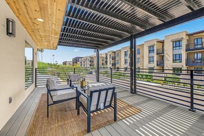 Un área de estar al aire libre, cubierta y con vistas a edificios residenciales.