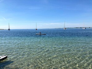 Ruhiges Meer mit klarem Wasser, Booten und einer entfernten Küste.
