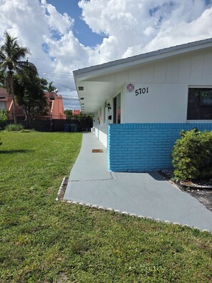 A building with a white and blue facade, a numbered address sign, and a visible door. - Entire 2/1 Rental Unit in Fort Lauderdale (Lauderhill)
