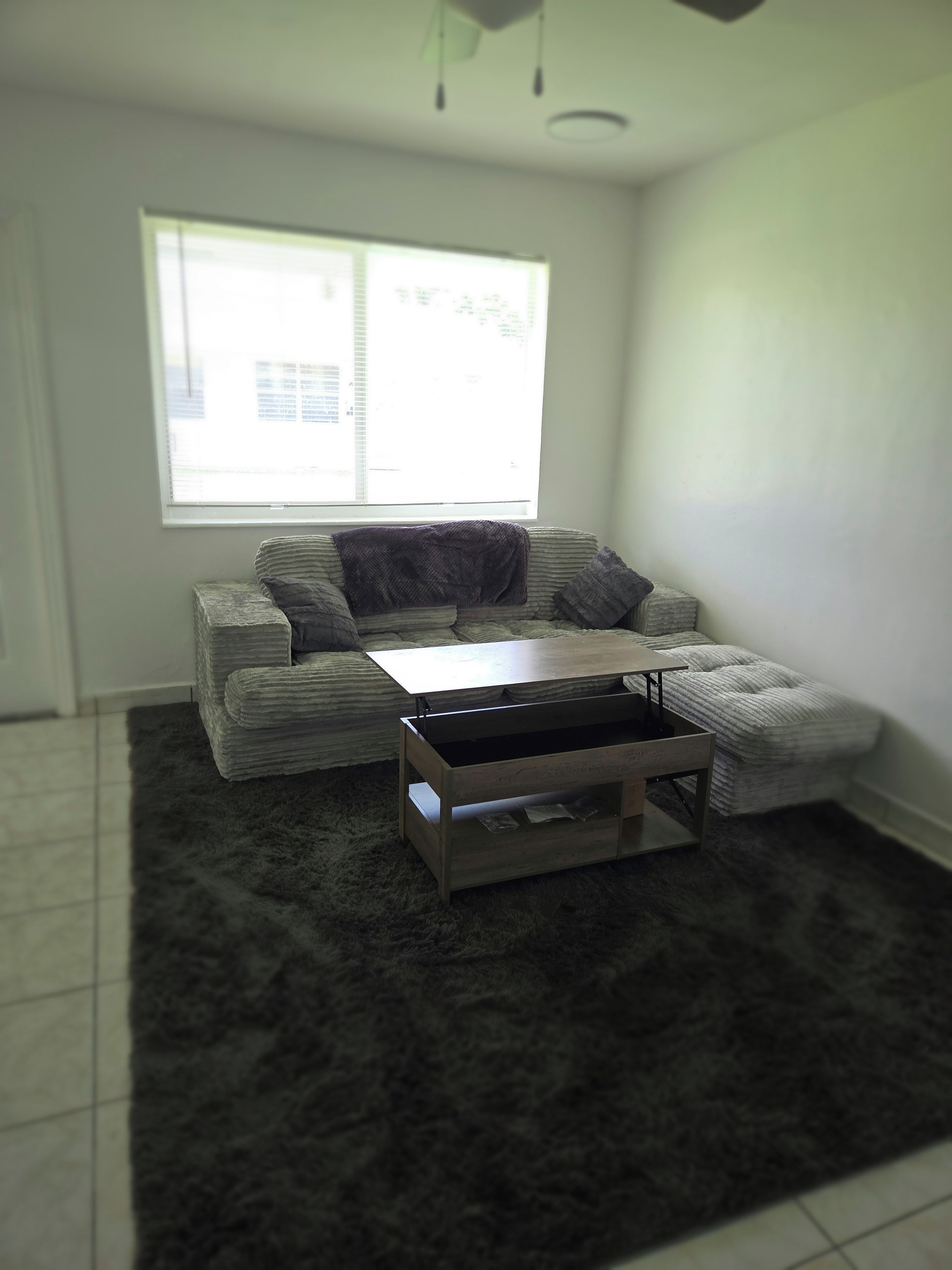 A living room with a sofa, a coffee table, and a window.