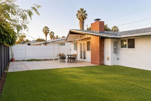 A residential backyard with a patio, a brick chimney, and a white fence. - Cozy 4BR Home Near Disneyland & Anaheim CC Sleep 15 (Anaheim)