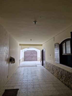 A corridor with tiled flooring, a tiled wall, a ceiling fan, and a large garage door. - Cozy family home where you can have good conversation and good food, good conversation and the beach. (Armação dos Búzios)