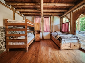 A wooden cabin interior with bunk beds, a small cabinet, and a window with curtains. - Bambu Guest House (Santa Cruz La Laguna)