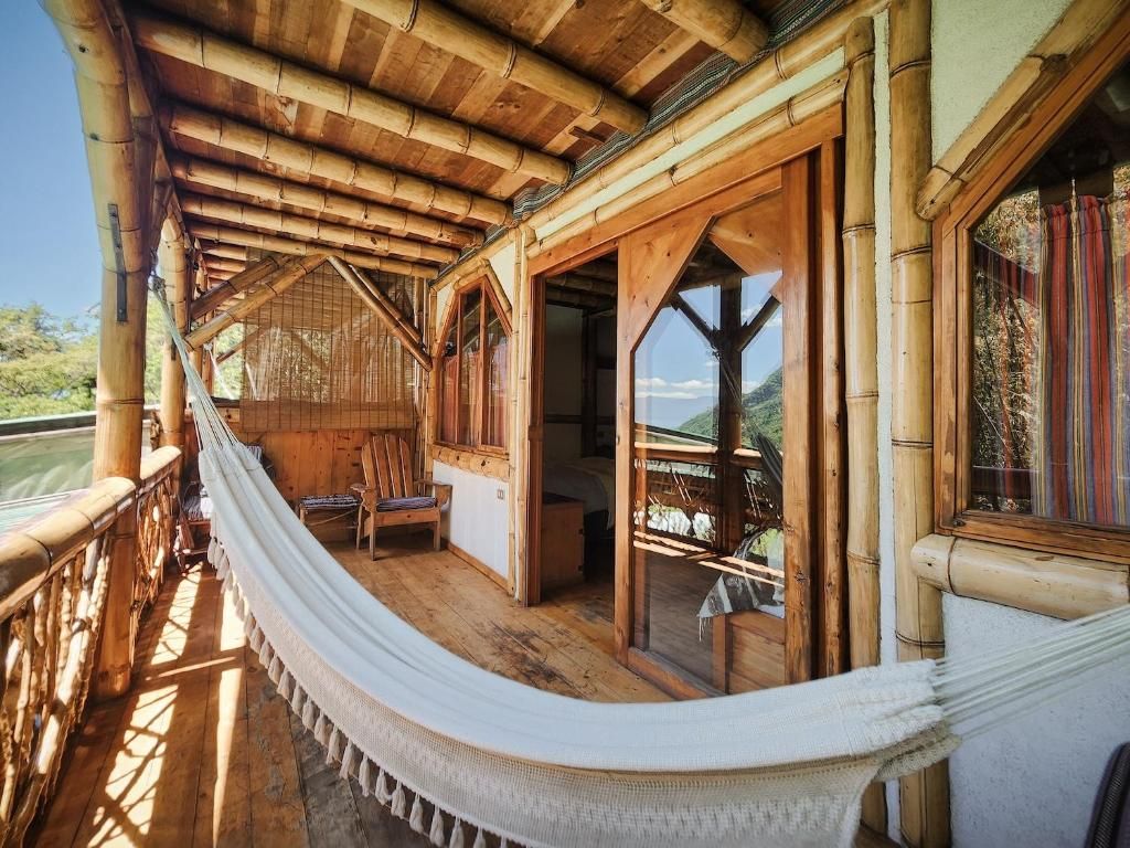 Un pontile in legno con un'amaca, mobili in legno e ampie finestre che offrono vista sul paesaggio.