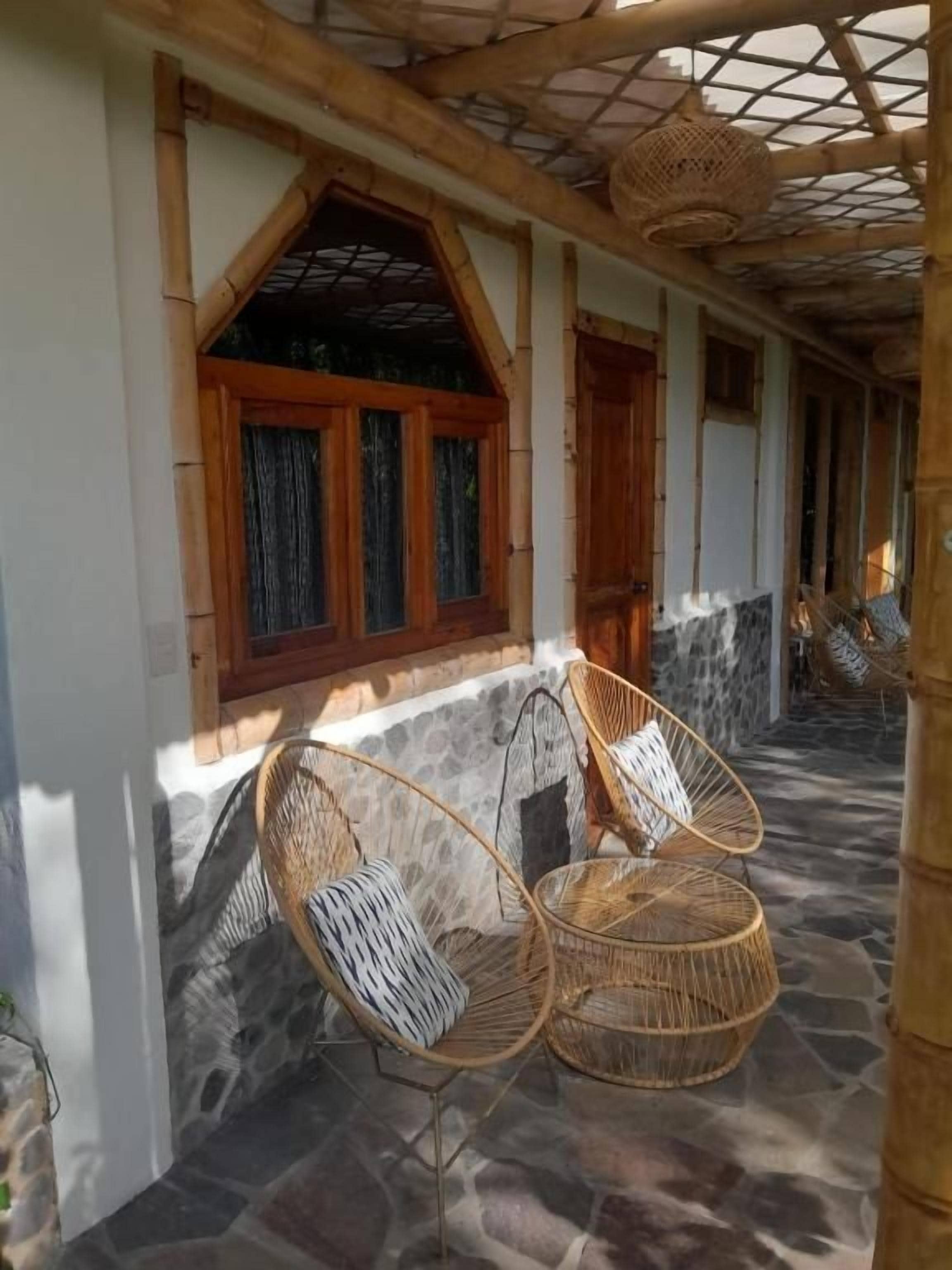 A covered outdoor seating area with wicker chairs and a stone floor.
