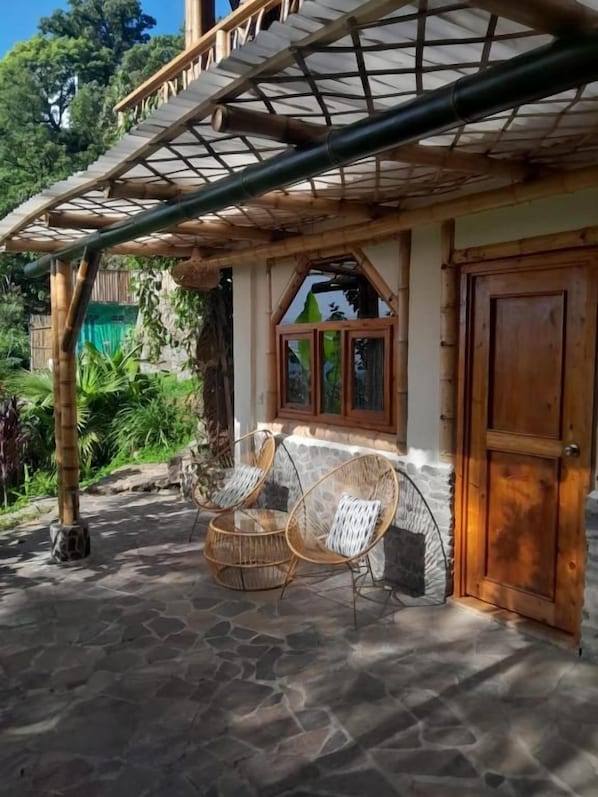 Un patio empedrado con dos sillas de mimbre y una puerta de madera.