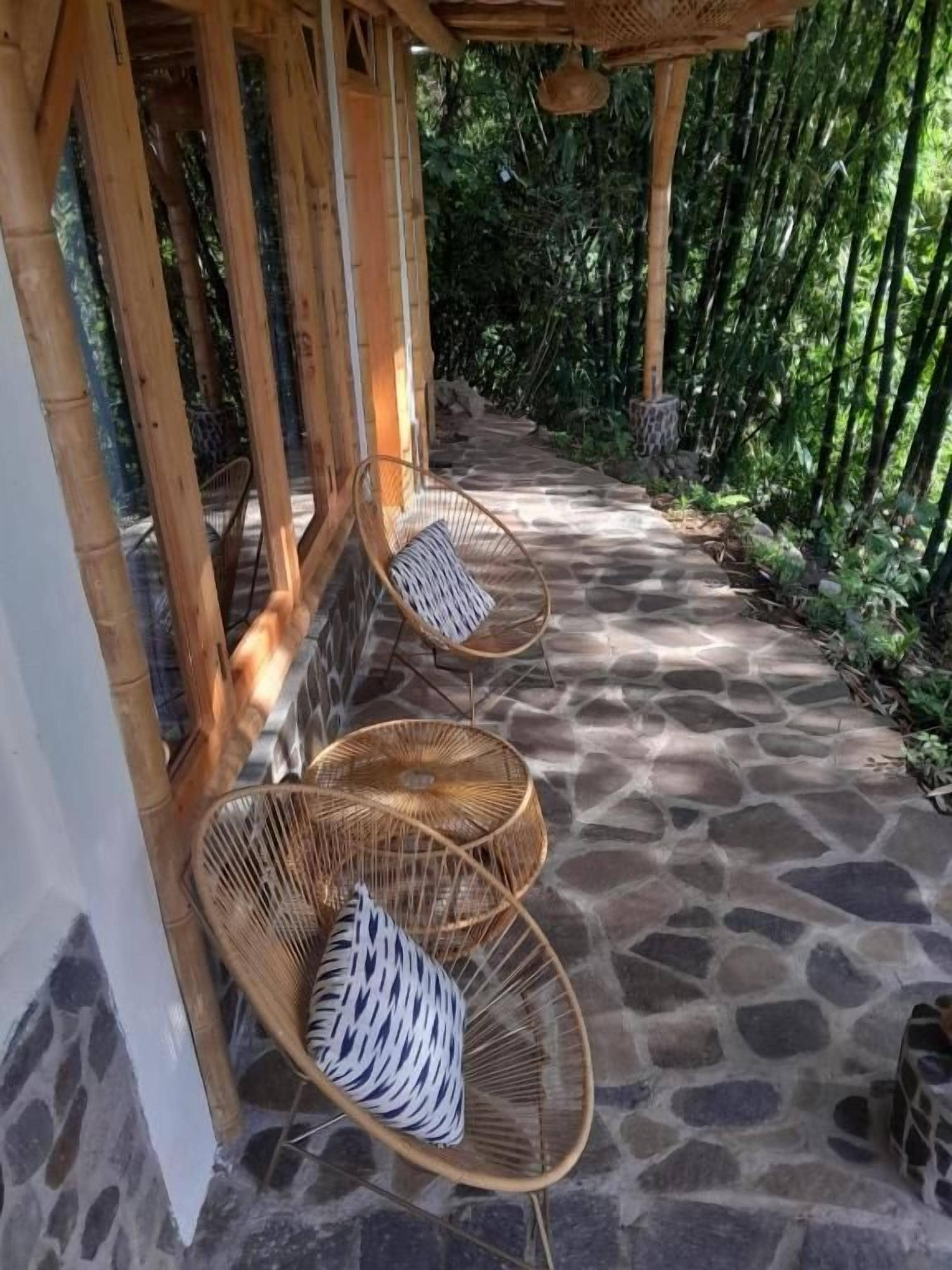 A covered outdoor seating area with stone flooring and wicker chairs.