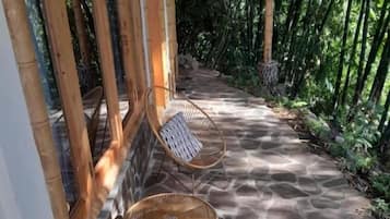 A covered outdoor seating area with stone flooring and wicker chairs.