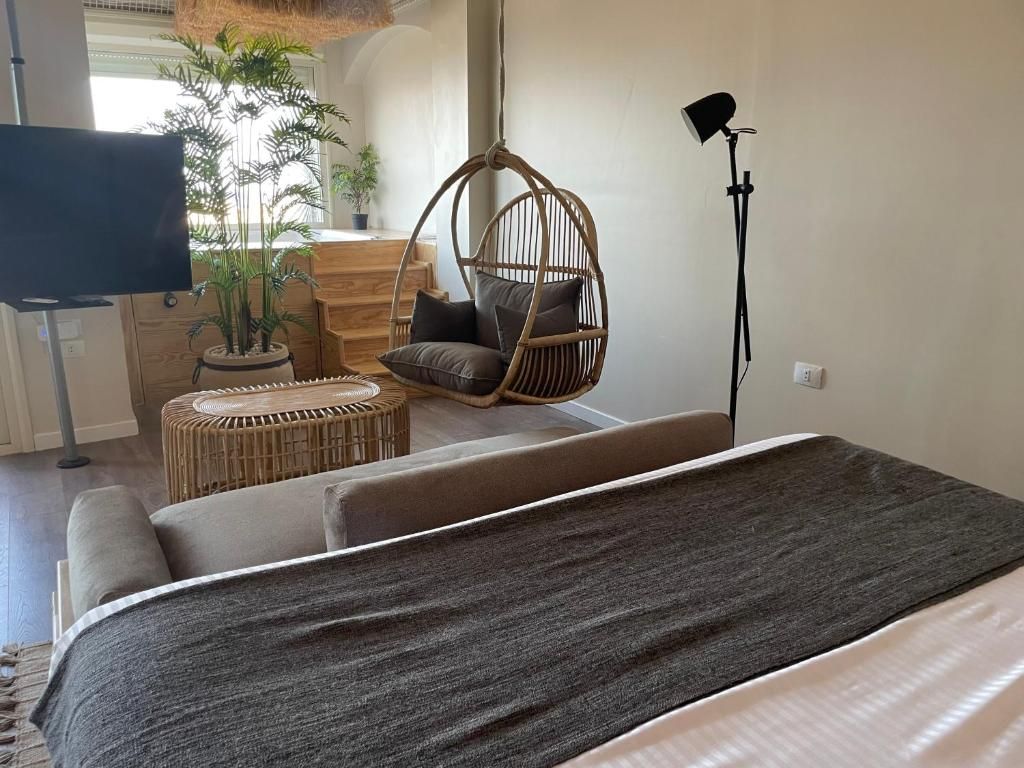 Een moderne kamer met een bed, een hangstoel, een klein rond tafeltje en een televisie.