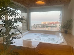 Un jacuzzi con vistas a un paisaje urbano a través de un amplio ventanal.