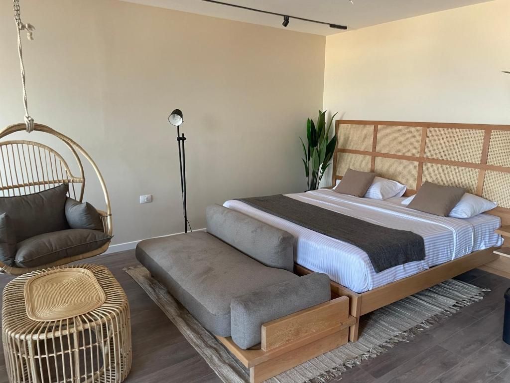 Un dormitorio con una cama, un sofá, una silla colgante y una lámpara de pie.
