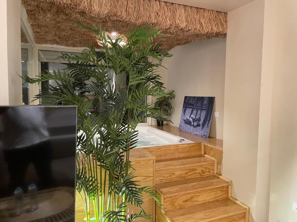 Una escalera de madera lleva a una habitación con una bañera y un cuadro en la pared.