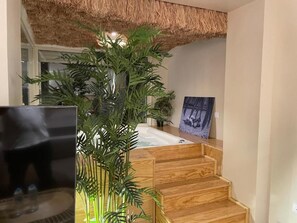 Een trap met houten treden die leidt naar een kamer met een badkuip en een schilderij aan de muur.