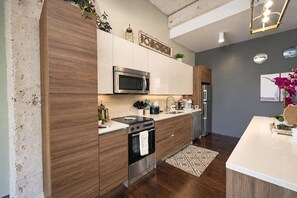 Una cocina moderna con armarios de madera, electrodomésticos de acero inoxidable y encimera blanca.