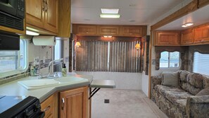 A compact RV interior with a kitchenette, a dining area, and a seating space. - Bunker Hill Hideaway Ramble RV Suite (Kingston)