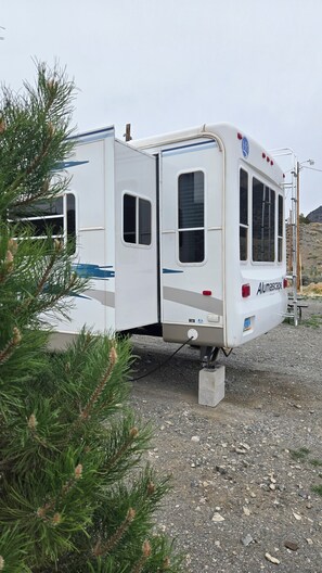 A stationary RV with a visible door, windows, and a license plate. - Bunker Hill Hideaway Ramble RV Suite (Kingston)