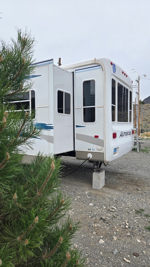 Een stilstaande caravan met een duidelijke deur, ramen en een kentekenplaat.