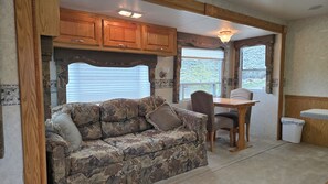A compact RV kitchen with wooden cabinets, a dining table, and a cushioned seating area.