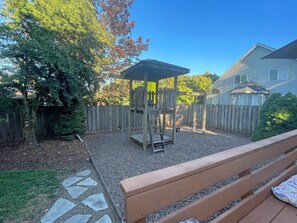 A backyard with a wooden play structure, a wooden fence, and a house in the background. - Family-Friendly Corvallis Home Near OSU & Parks (Corvallis)