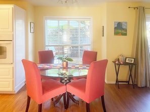 A dining area with a glass table, red chairs, a potted plant, and a view through the window. - Family-Friendly Corvallis Home Near OSU & Parks (Corvallis)