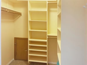 Un placard avec plusieurs étagères et une porte en bois.