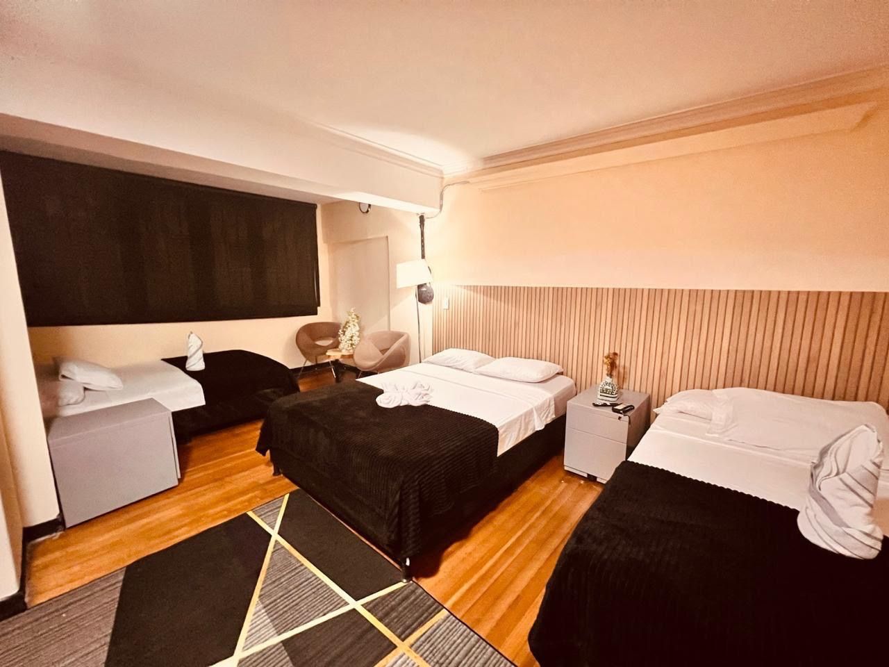 Habitación de hotel con dos camas, un escritorio, una silla y una mesita de noche.