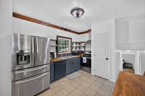 A modern kitchen with stainless steel appliances, a window, and wooden beams on the ceiling.