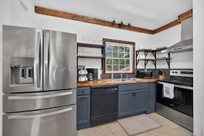 Una cocina moderna con electrodomésticos de acero inoxidable, horno empotrado y ventana sobre el lavabo.
