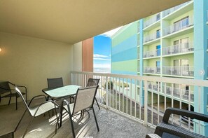 Un balcon avec une table et des chaises, donnant sur un immeuble doté de nombreux balcons.