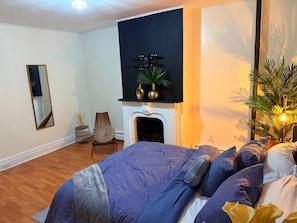 Une chambre à coucher avec un lit, une cheminée, un miroir et une plante.