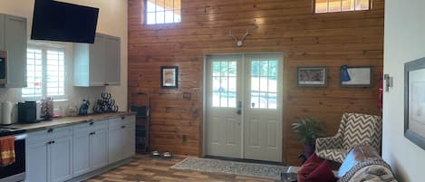 A spacious living area with a wooden wall, a ceiling fan, a television, and a sofa.