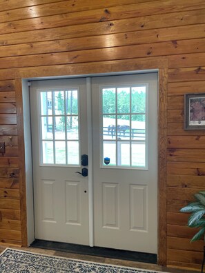 A wooden double door with a window, a doorknob, and a small sign on the door. - Delightful 1-Bedroom Barn Apartment Located In Gated Equestrian Community (Aiken)