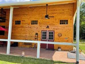 A wooden cabin with a porch, a red door, and a ceiling fan. - Delightful 1-Bedroom Barn Apartment Located In Gated Equestrian Community (Aiken)