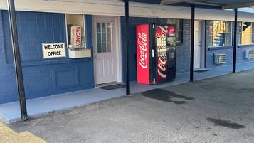 A building with a 'Welcome Office' sign, a Coca-Cola vending machine, and a door.