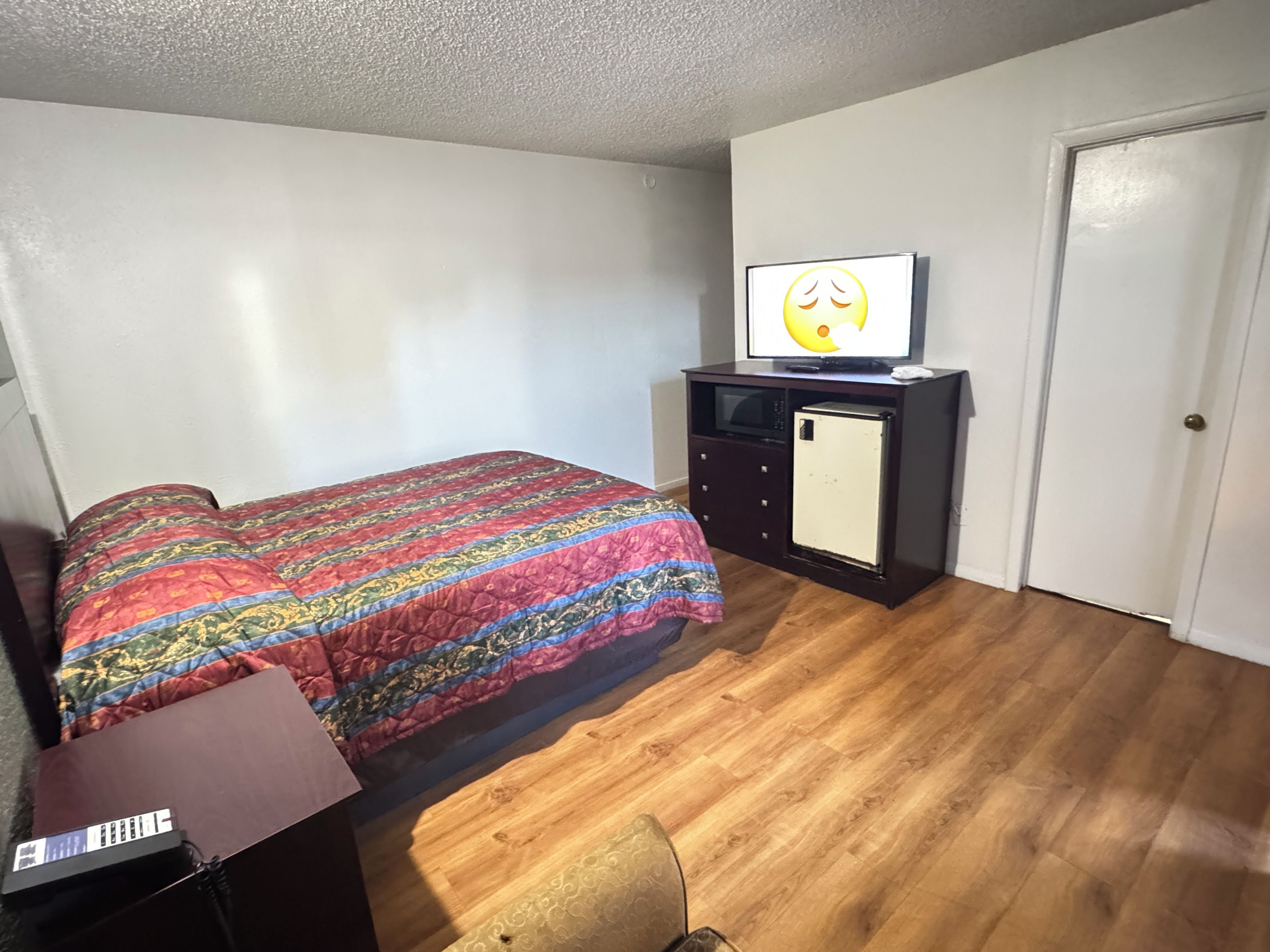 Un dormitorio con una cama, un televisor sobre un tocador y una puerta.