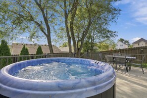 An outdoor hot tub with a wooden deck and metal railings, surrounded by trees and residential buildings. - Kentucky Getaway/Hot Tub (Georgetown)
