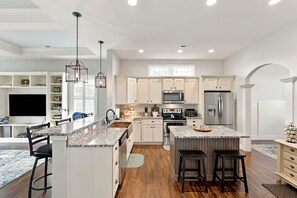 A modern kitchen with white cabinetry, a central island, stainless steel appliances, and pendant lighting. - Kentucky Getaway/Hot Tub (Georgetown)
