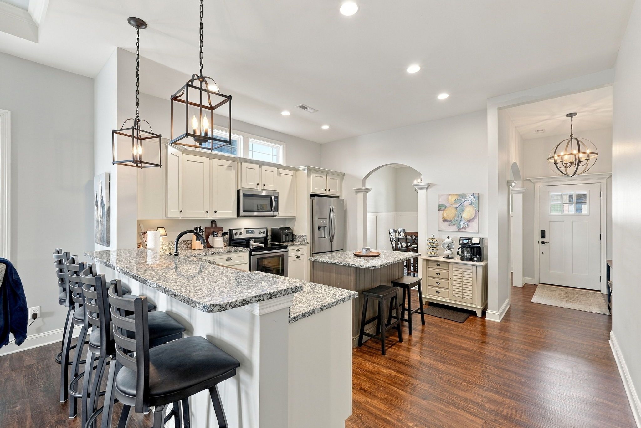 A modern kitchen with white cabinetry, granite countertops, and stainless steel appliances.